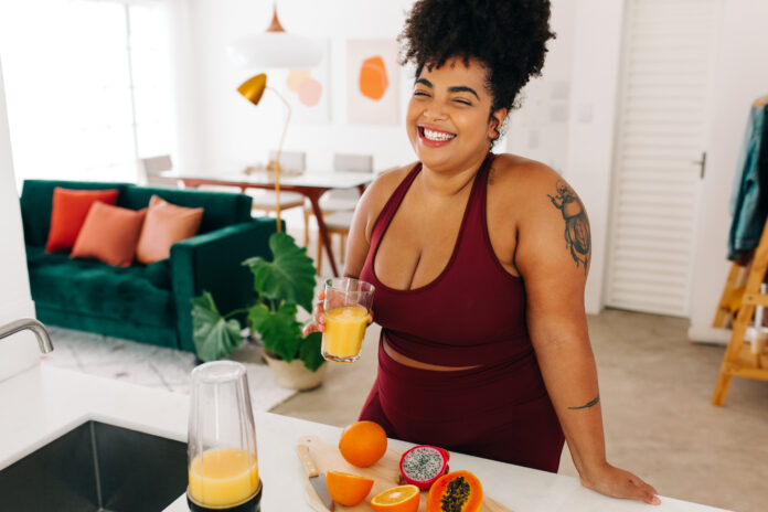 Woman in sportswear having fruit juice at home.