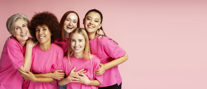 Women with pink ribbon isolated on background, copy space. Breast cancer awareness month