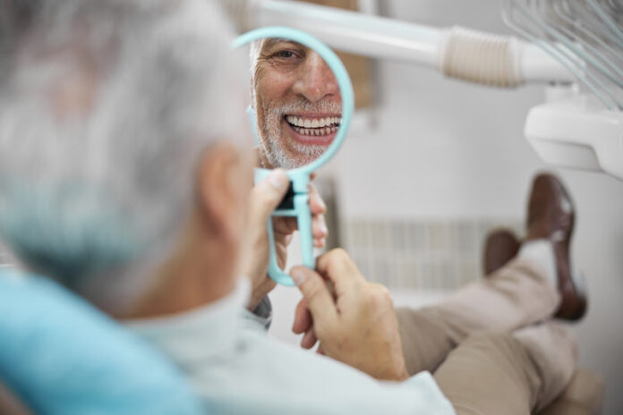Aged patient sitting in a dental chair while looking at himself in the mirror